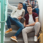 teenage schoolboys sitting on stairs at school and looking at camera